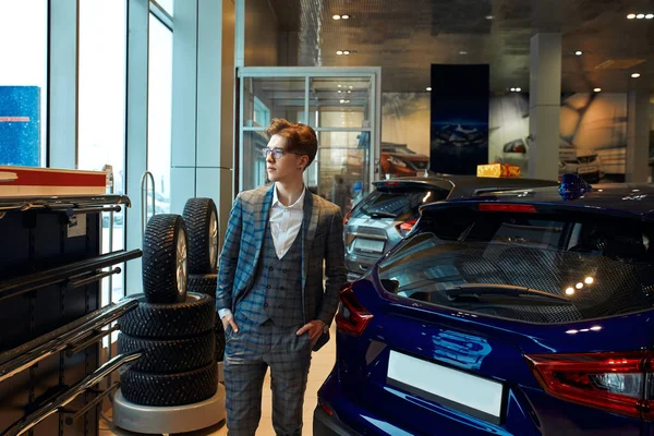 Serious man standing next to cars in a dealership — Stockfoto