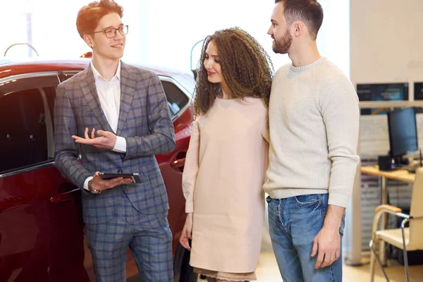 Young friendly man asking clients to make test drive, try to drive — Stockfoto