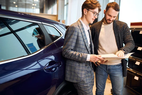 Happy man buying a new car at vehicle show room — Stockfoto