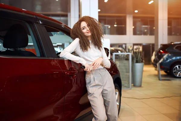 Attractive happy car owners posing to the camera in the show room — ストック写真