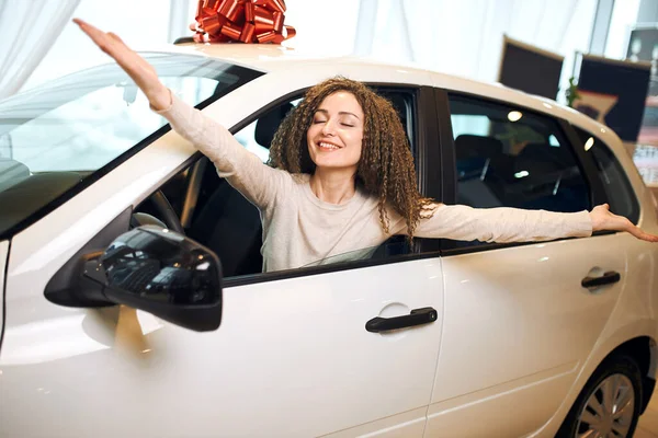 Overjoyed happy excited girl sitting in the luxury car with wide opened arms — Stockfoto
