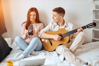 attractive styluish girl holding a camera, looking at it