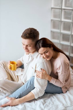 young man holding a yellow mug and striking his wifes leg