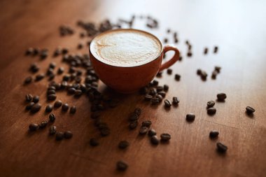 Steaming cup of latte with heart shape few coffee beans. still life