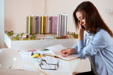 beautiful young awesome female architect drawing model in the paper