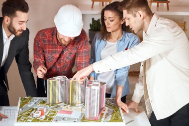 Team of engineers styding a model of building complex at meeting