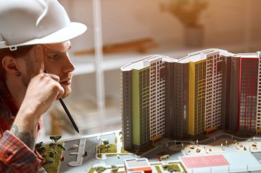 serious man looking at model of house