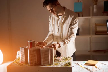 young blonde guy using engineering tools while working in a model office