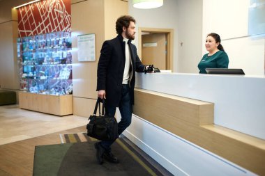 young tourist talking with receptionist about the prises of rooms