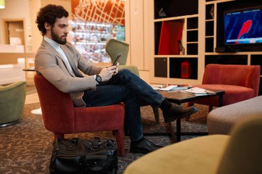 young handsome bearded man sitting with crossed legs on the armchair