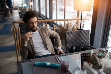 Young serious man making a phone call in coffee shop