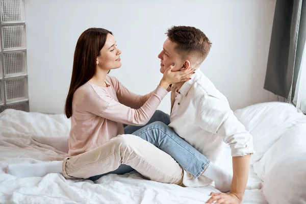 Menina encantadora em camisola bege e jeans flertando com seu namorado bonito — Fotografia de Stock