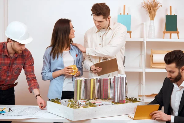 blonde guy holding a folder and putting his hand on his colleagues shoulder