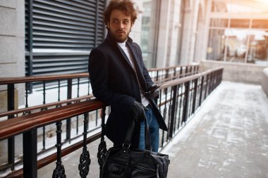 smiling attractive guy using cellphone and smiling while leaning stairs outdoors