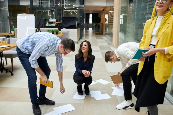 cheerful funny business people gathering thrown paper which are lying