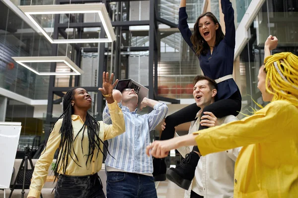 Equipo multirracial excitado divertirse montar en la sala de oficina — Foto de Stock