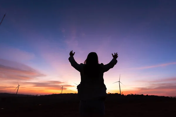 シルエットのツーリストの女性はタービンの夕日に手を上げてください。 — ストック写真