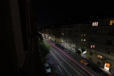 Alman şehrinde eski apartmanları ve trafiği olan bir yolun gece görüşü