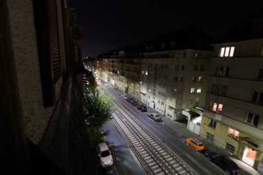 Alman şehrinde eski apartmanları ve trafiği olan bir yolun gece görüşü