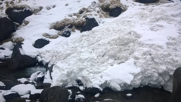 L'eau coule sous la neige et la glace dans un froid — Photo