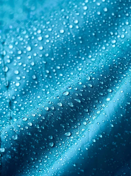 Mavi fiber su geçirmez kumaş üzerine yağmur damlacıkları. Mavi arkaplan.