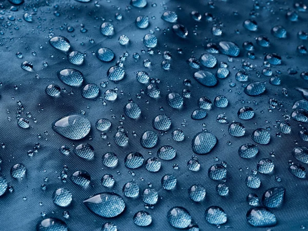 蓝色纤维防水织物上的雨滴 蓝色背景 — 图库照片