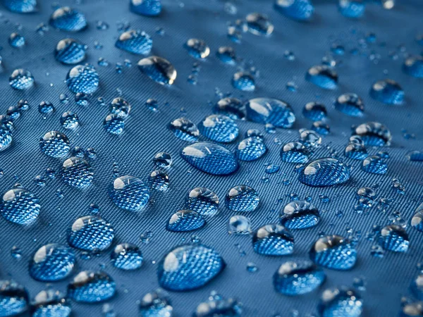 Mavi fiber su geçirmez kumaş üzerine yağmur damlacıkları. Mavi arkaplan.