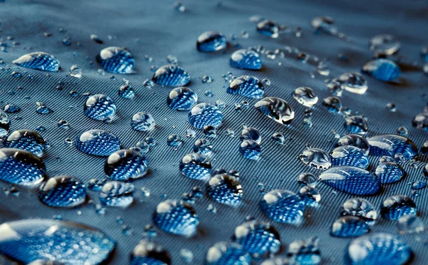 Mavi fiber su geçirmez kumaş üzerine yağmur damlacıkları. Mavi arkaplan.