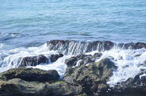 Onde marine che si infrangono sulle rocce creando schiuma — Foto Stock