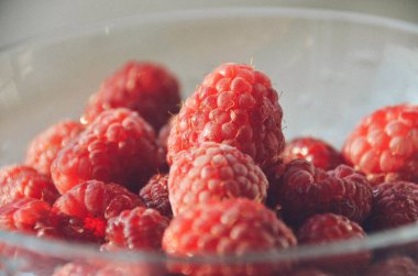 Cam kasede bir avuç olgun ahududu. Parlak kırmızı böğürtlenler yakın