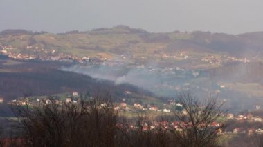 İlkbaharda köy manzarası, tepe ve evlerin üzerinden duman çıkan ateş...