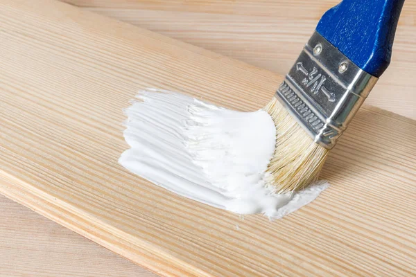 Blauer Pinsel in weißer Farbe auf einem hellen Holzbrett. Malen Sie im Hugg-Stil. Selektiver Fokus, Kopierraum — Stockfoto