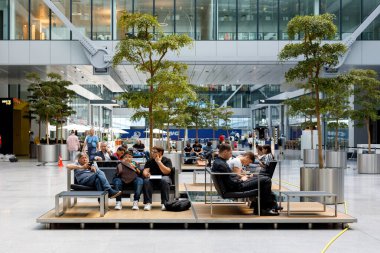 Almanya, Frankfurt, 16 Ağustos 2019: Yolcular Frankfurt Havaalanı 'nın fütürist salonunda bir uçuş bekliyorlar. Yeşil modern ulaşım ve iş merkezi kavramı, doğa ve teknolojinin birleşimi