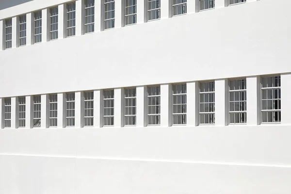 The new white plastered wall of the building with a series of barred windows. The concept of restriction of freedom, imprisonment, prison — Stock Photo, Image