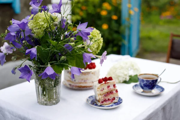 Homemade cake and a bouquet of flowers on a table in a summer garden — Stock Photo, Image