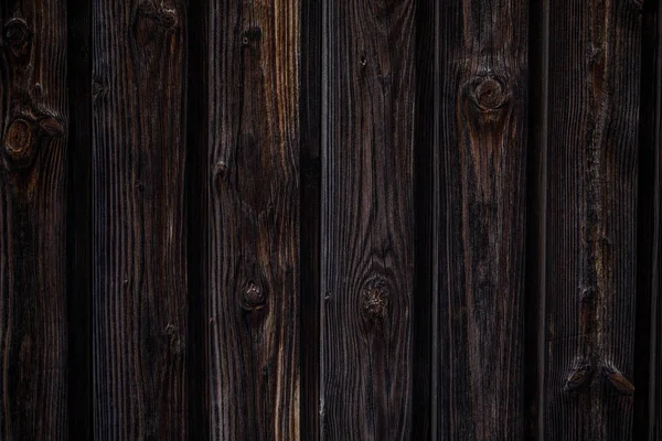 Donker bruine houten achtergrond. Verticale planken met knopen, donkere kleur. — Stockfoto