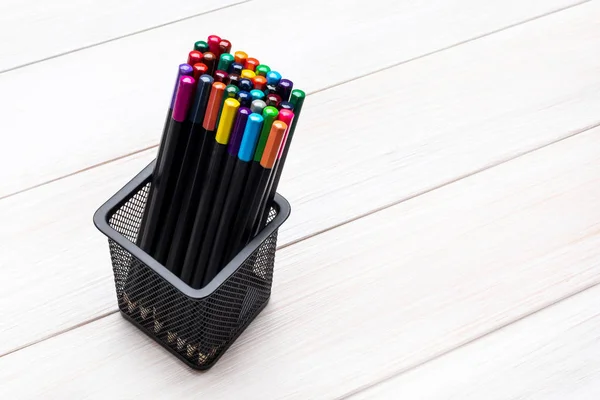 Different color pencils in a black office cup on a light wooden table. View from above — Stock Photo, Image