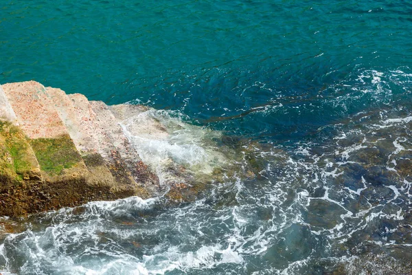 A reliable stone staircase descends into the water of the Atlantic Ocean on a sunny summer day. Sea waves crash on a solid staircase. — Stock Photo, Image