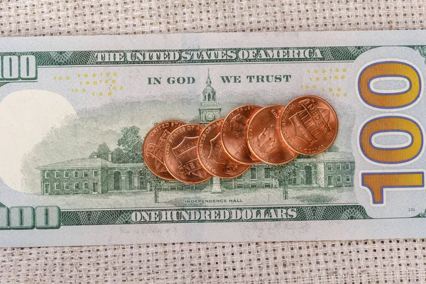 Ein paar Cent-Münzen auf einem Hundert-Dollar-Schein — Stockfoto