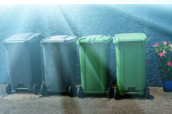 Four plastic dumpsters against the blue wall in the sunlight. — Stock Photo, Image