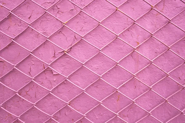 Metal wire grill on the background of an old pink wall with peel — Stock Photo, Image