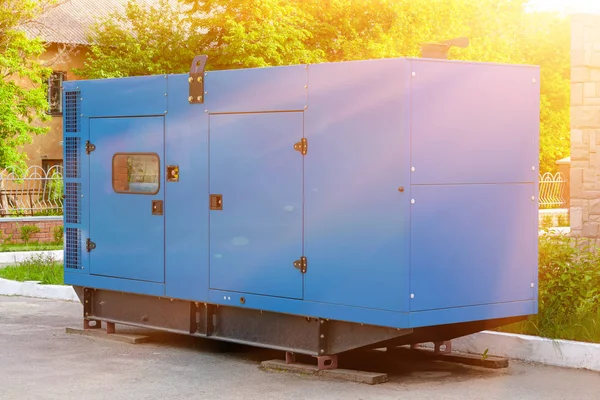 Diesel generator for emergency power supply at the wall of a medical center against the backdrop of green trees in fine sunny weather. — Stock Photo, Image