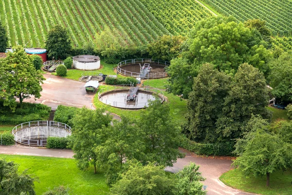 Sewage treatment plant next to the green trees and fields. Image to demonstrate good recycling, environmental friendliness of the process. View from the top