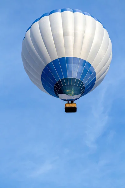 A white-blue balloon is high in the sky. There is a blue sky with a white balloon. view from below. Copy space