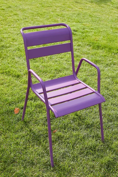 One purple chair on a green lawn. The concept of free vacancy, loneliness, desolation. For the image of empty public space, open opportunities. — Stock Photo, Image