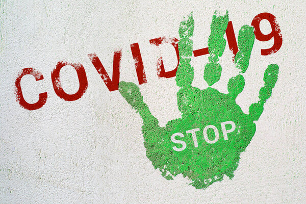 Green handprint with the inscription STOP on the inscription COVID-19. End of quarantine, reduction of viral hazard. The hope of improving the epidemiological situation, ending the pandemic
