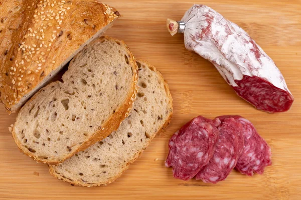 Κομμένο Ψωμί Δημητριακών Και Φέτες Αποξηραμένου Ιταλικού Λουκάνικου Μια Ξύλινη — Φωτογραφία Αρχείου