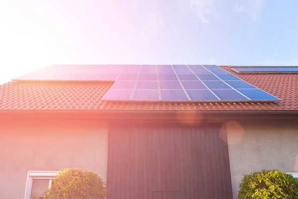 Solar panels on the tiled roof of the building in the sun set.