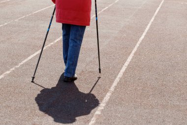 Evinin yakınındaki bir spor sahasında yürüyen yaşlı bir kadının bacakları. NCOV-19 Coronavirus salgını sırasında kendini izole etme. Yaşlılık konseptinde spor yaşam tarzları.