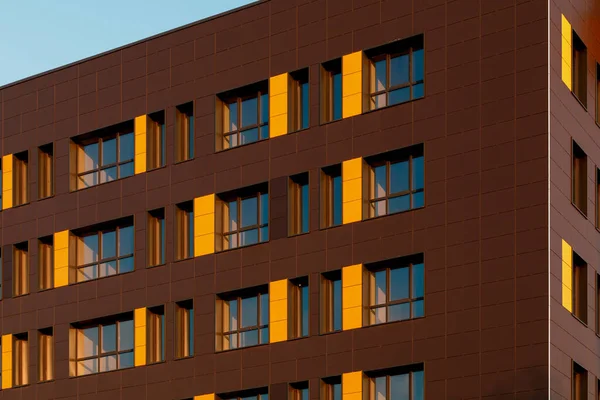 Fragment of a new elite house or residential complex. Part of urban real estate. Windows on a yellow-brown modern ventilated facade. — Stock Photo, Image